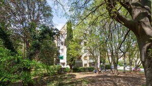 A courtyard with trees, a building with balconies, and parked cars. - 1 bedroom nice apartment in Pula (Pula)