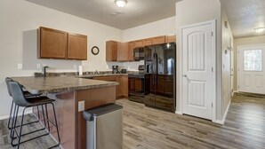 A modern kitchen with wooden cabinets, a stainless steel refrigerator, and a built-in island with bar stools.