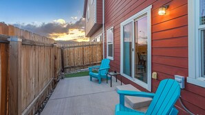 A patio with two blue Adirondack chairs, a concrete walkway, and a wooden fence.