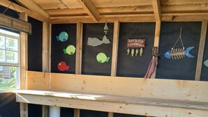 A room with a bunk bed, a white chair, and a wall decorated with fish cutouts and a welcome sign. - Russell's Roost Camping , Boating, Fishing ON Martiny Chain of Lakes. (Barryton)