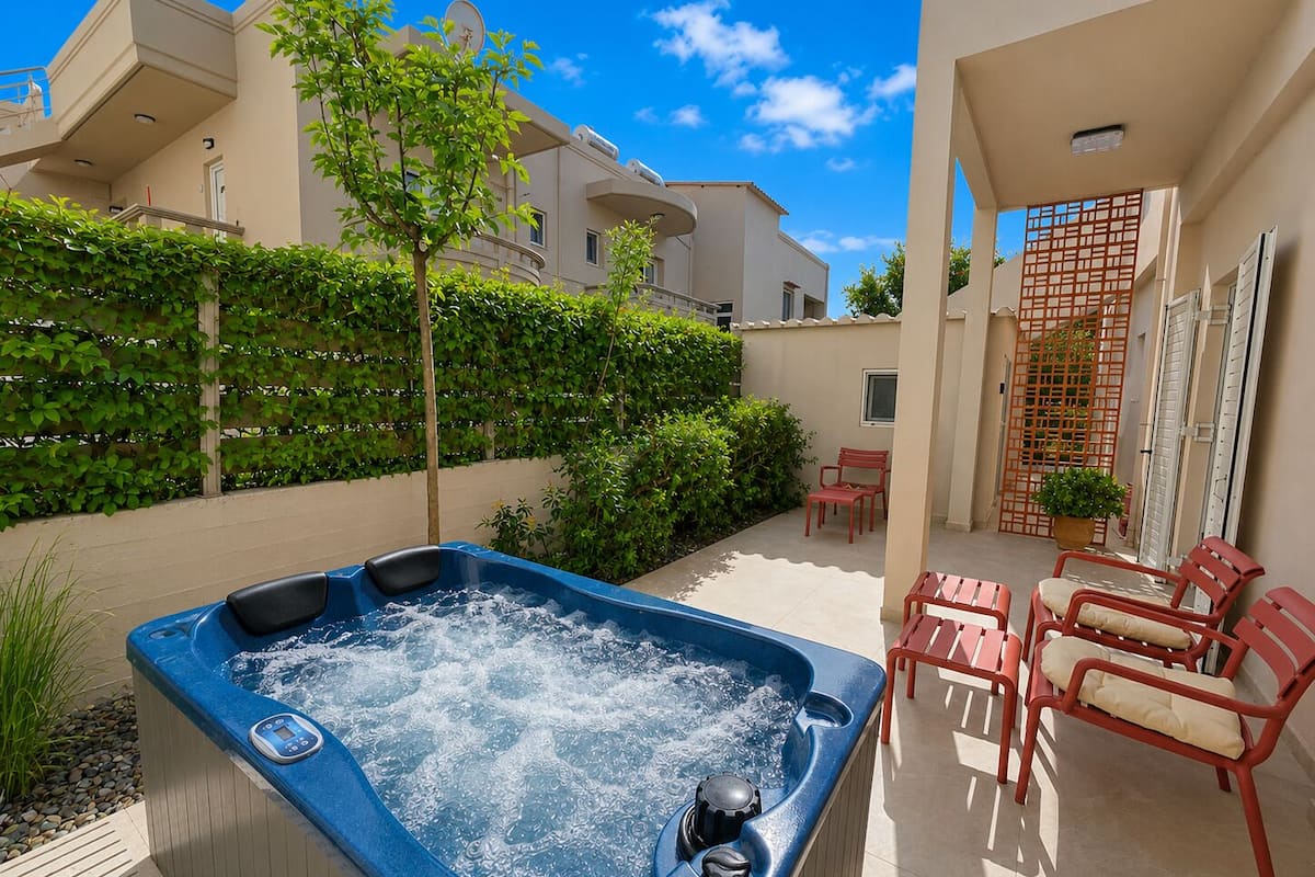 A hot tub with a control panel, surrounded by red chairs and a potted plant.