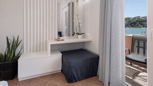 A modern bathroom with a white vanity, a large mirror, and a view of the sea. - Elena SeaFront Luxury Apartments (Apokoronas)
