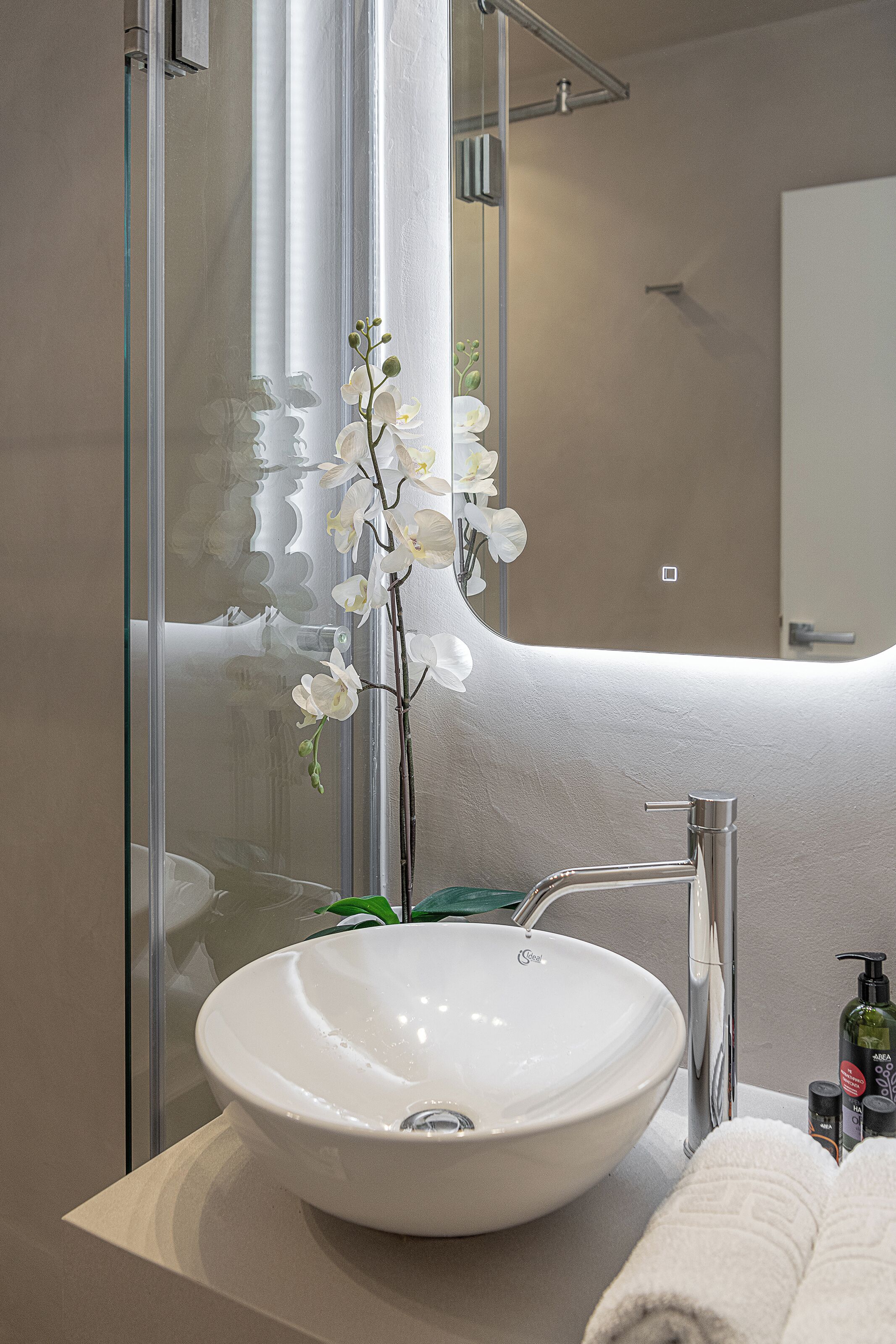 A bathroom with a white sink, a glass shower enclosure, and a mirror.