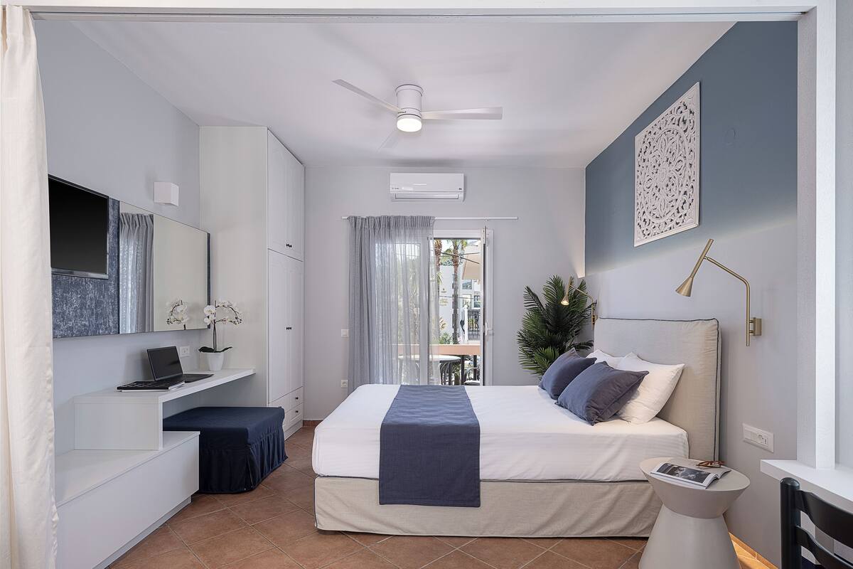 A modern bedroom with a bed, a desk, a chair, and a small table.