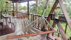 A hammock suspended from a wooden structure with a patterned rug on the floor.