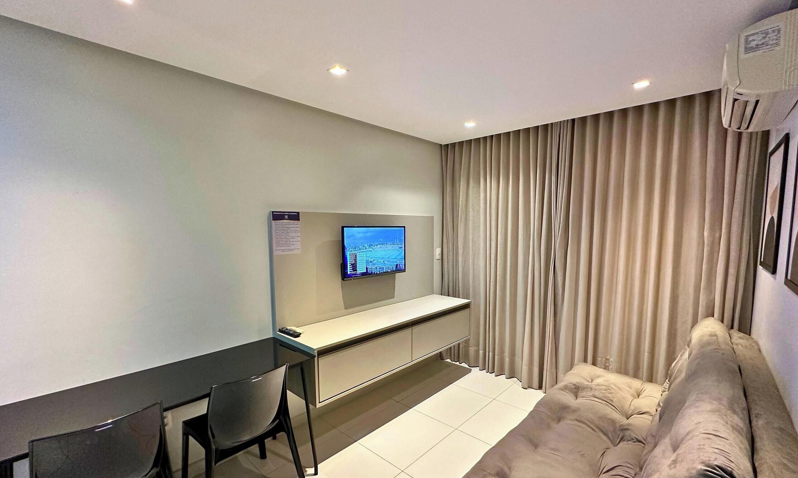 A hotel room with a bed, a desk, a chair, a television, and curtains.