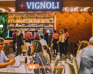 A restaurant interior with a Vignoli sign, bar area, and dining tables.