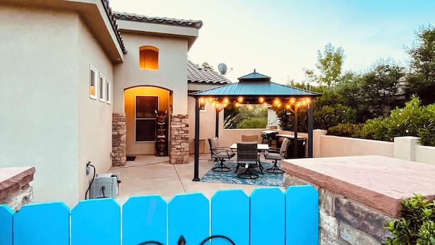 A patio area with a covered seating area, a stone wall, and a blue fence.