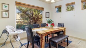 A dining area with a wooden table, black chairs, a high chair, and a chandelier.