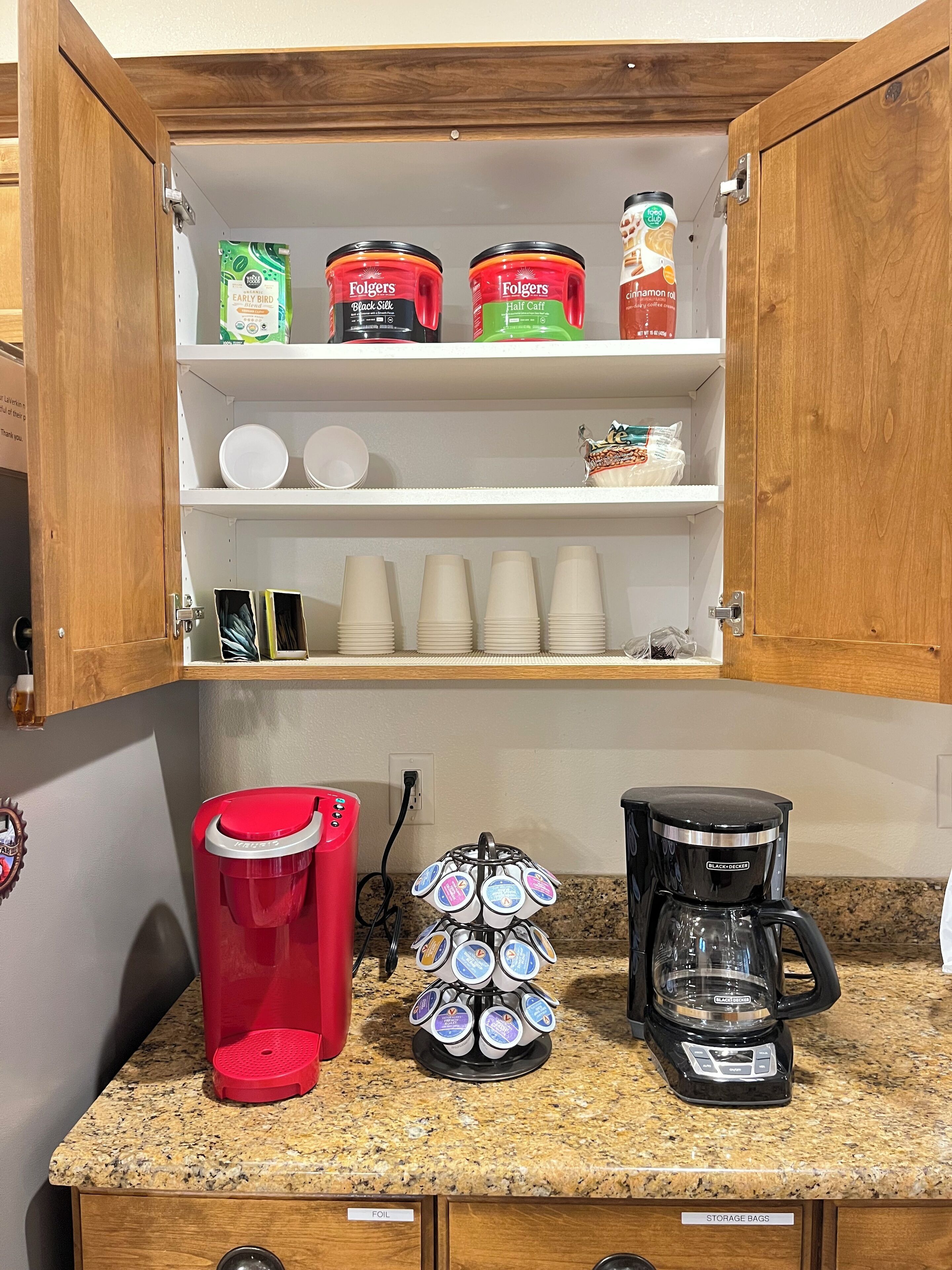 A kitchen with a coffee station, including a coffee maker, a red coffee pot, and a mug rack.