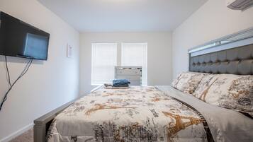 A bedroom with a bed, a television, and a window with blinds.