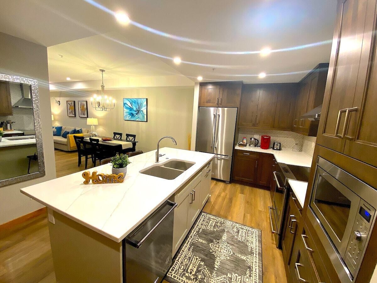Een moderne keuken met een centraal eiland, roestvrijstalen apparatuur en een zithoek met een bank en tafel.