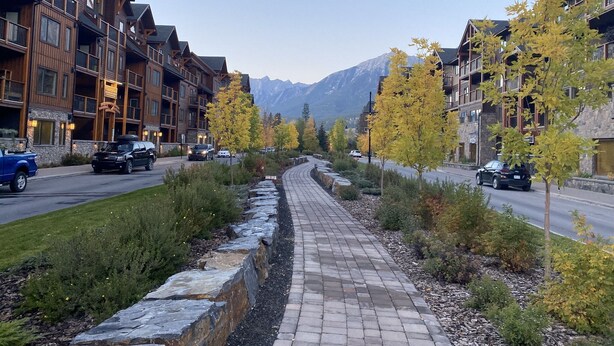 A multi-story hotel with balconies, a paved walkway, and a mountain backdrop. - Luxury, Spacious, New, Entire Condo Suite, Scenery Year-round Mountain Getaway (Canmore)