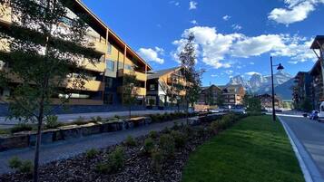 A modern building with multiple floors, a paved walkway, and a grassy area.