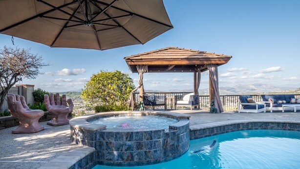 Ein Pool mit Whirlpool, Gartenmöbeln und einer Pergola.