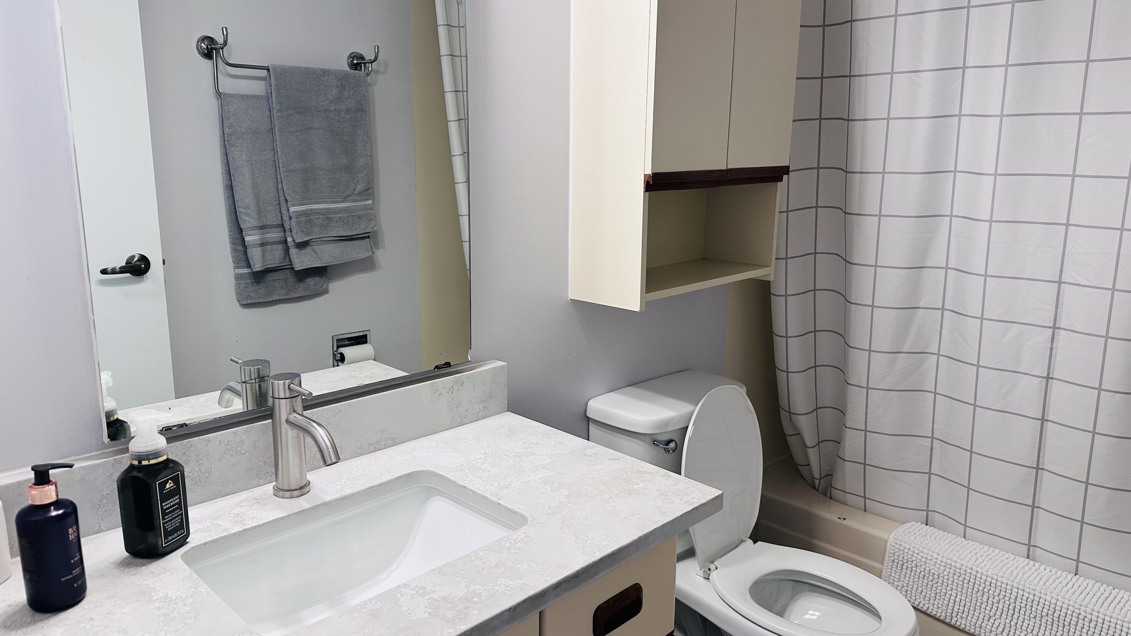 Ein Badezimmer mit Waschbecken, Toilette, Spiegel und Handtuchhalter.