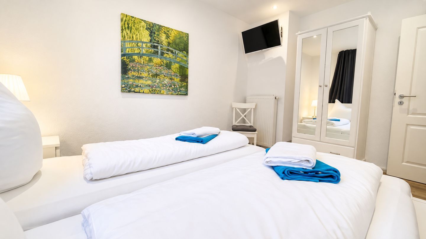 Ein Hotelzimmer mit zwei Betten, einem Bild an der Wand, einem Fernseher und einem Kleiderschrank.