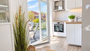 Eine moderne Küche mit einem großen Fenster, einem eingebauten Backofen und Blick ins Freie.