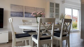 Ein Essbereich mit weißen Stühlen, einem weißen Tisch und einer Blumenvase.