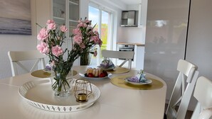 A dining table with pink flowers, a candle, and a fruit plate.