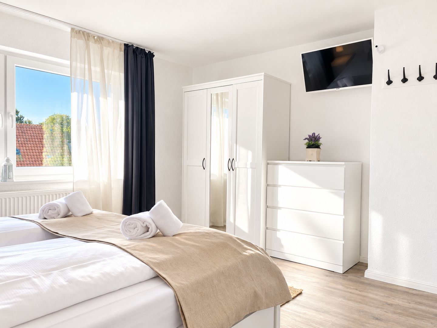 A hotel room with a bed, a wardrobe, a television, and a window with curtains.