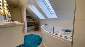 Un baño moderno con tragaluz, una bañera, un tocador con espejo y una planta en maceta.