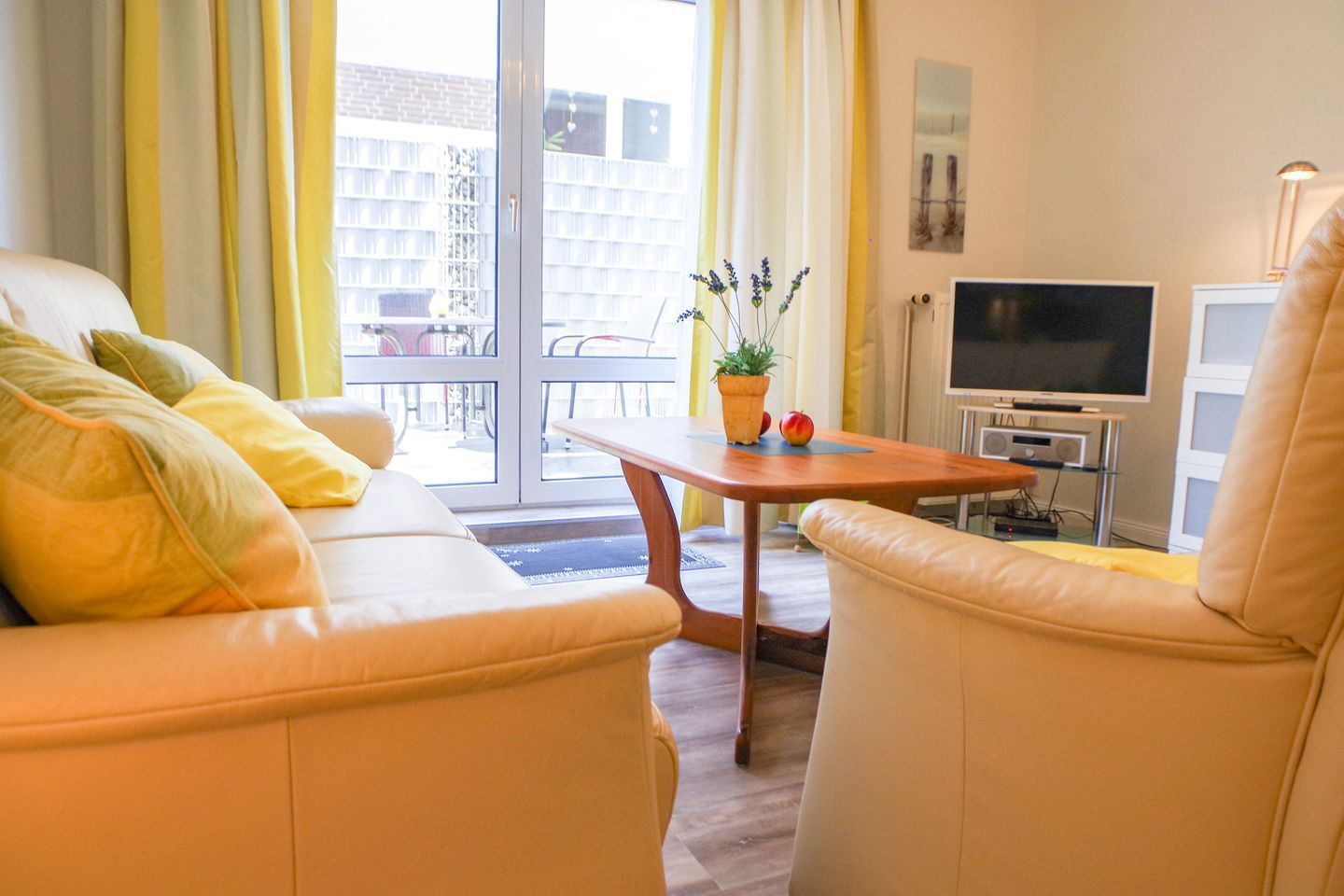 Ein modernes Wohnzimmer mit einer Couch, einem Sessel und einem kleinen Tisch mit Pflanze und Obst.