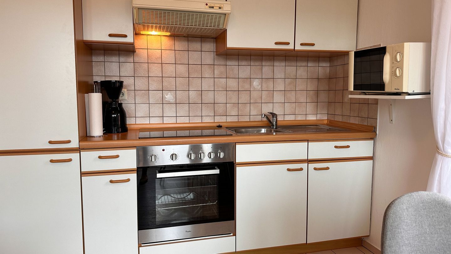 Eine Küche mit Backofen, Mikrowelle und Kaffeemaschine.