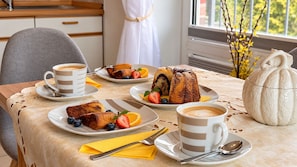 Desayuno servido con platos de comida, tazas de café y un jarrón decorativo.