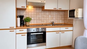 Una cocina compacta con horno empotrado, microondas y pileta.