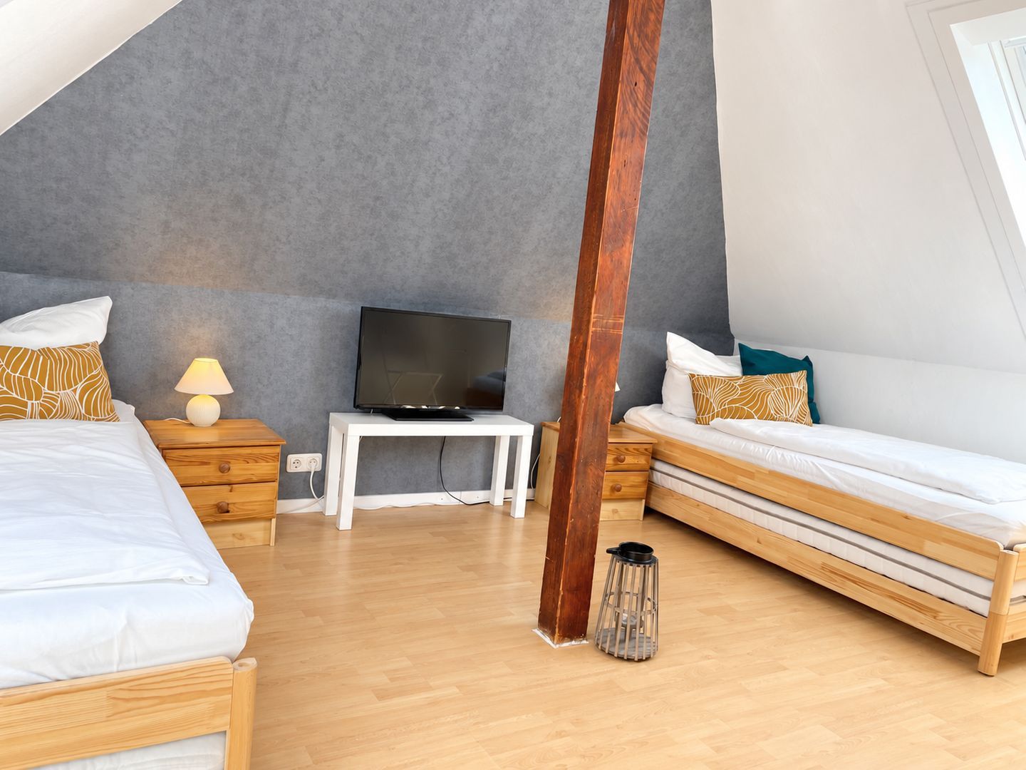 Ein modernes Schlafzimmer mit zwei Betten, einem Fernseher und einem kleinen Tisch.