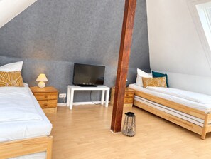A modern bedroom with two beds, a television, and a small table.