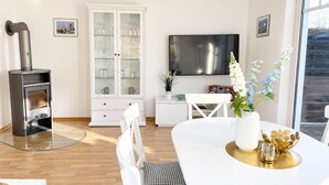 Ett modernt vardagsrum med en öppen spis, en matplats och en tv.