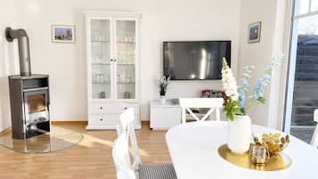 Ein modernes Wohnzimmer mit Kamin, Essbereich und Fernseher.