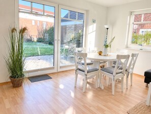 Un comedor moderno con una mesa redonda, sillas blancas y una planta en maceta.