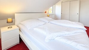 Ett hotellrum med en säng, ett nattduksbord, en lampa, en garderob och ett fönster som släpper in naturligt ljus.