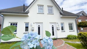 A two-story house with a white exterior, numbered doors, and a brick pathway leading to the entrance.