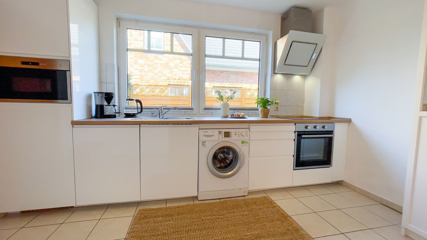 A compact kitchen with a washing machine, oven, and coffee maker.