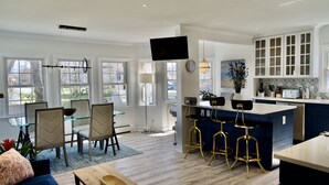 A modern kitchen with a large island, bar stools, and a flat-screen TV. - 5 minute walk to beach, walk to town & train (Fairfield)
