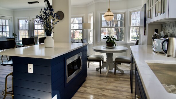 A modern kitchen with a blue accent island, a round dining table, and large windows. - 5 minute walk to beach, walk to town & train (Fairfield)