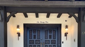 A dark wooden double door with intricate carvings and two wall-mounted lights on either side. - Welcome to The Urban Mansion in Midtown Tallahassee (Tallahassee)