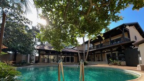 A swimming pool with a wooden deck, surrounded by a building with a balcony and a covered patio area. - Welcome to The Urban Mansion in Midtown Tallahassee (Tallahassee)