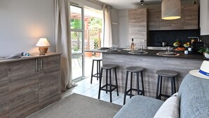 Una cocina moderna con una isla central, taburetes de bar y un rincón comedor con sofá.