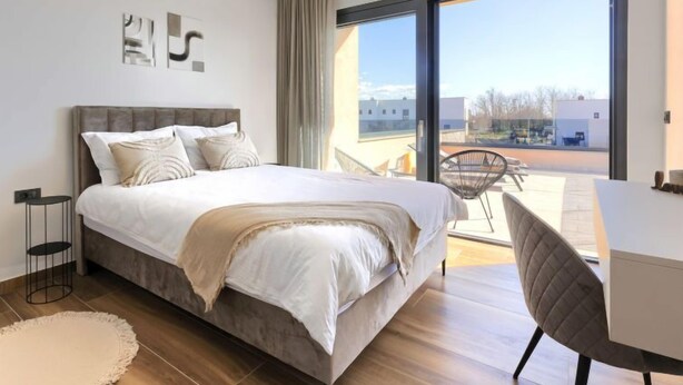 Ein modernes Schlafzimmer mit einem großen Bett, einem Schreibtisch und Blick ins Freie.