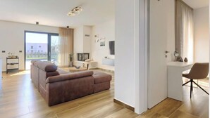 Ein modernes Wohnzimmer mit einer Couch, einem Fernseher und einem Schreibtisch mit Stuhl.