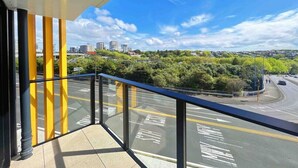 Ein Balkon mit Blick auf eine Stadtlandschaft, einschließlich Straßen und Gebäuden.