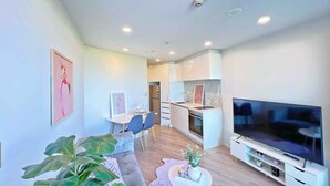 Eine moderne Wohnung mit Wohnzimmer, Essbereich, Küchenzeile und Fernseher.