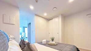 Ein Hotelzimmer mit einem Bett, einem Nachttisch, einer Wandleuchte und einer Tür zu einem Badezimmer.