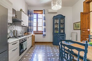 A kitchen with a tiled floor, a stove, cabinets, and a dining table with chairs.