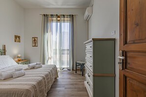 A bedroom with a bed, a dresser, a nightstand, a chair, and a window with curtains.